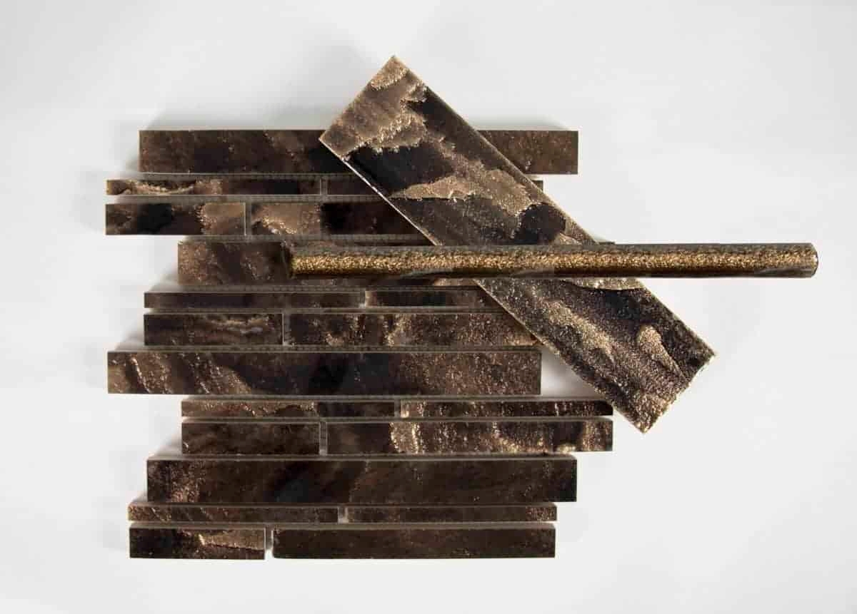 A collection of dark, textured tiles arranged in a staggered pattern, including a decorative piece that stands out horizontally.