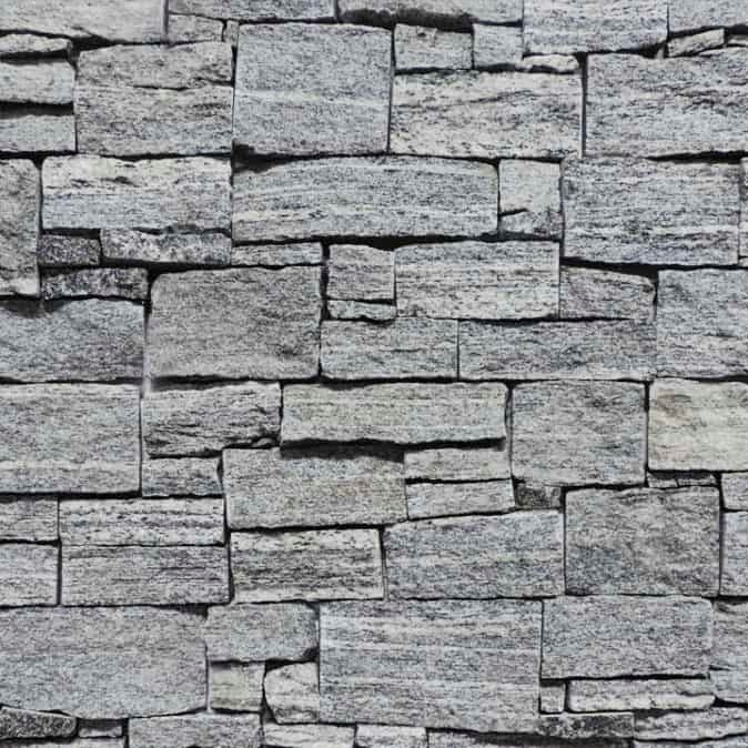 A textured wall made of various gray stone blocks arranged in a patterned manner.