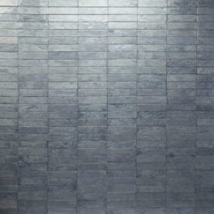 A textured gray wall made of rectangular stone tiles arranged in a uniform pattern.