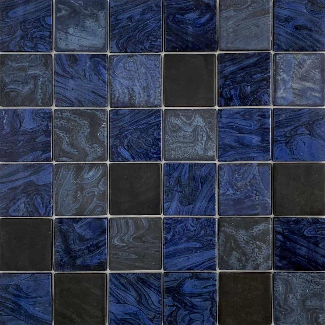 A mosaic of square tiles in shades of blue and black with varied textures and patterns, arranged in a grid layout.