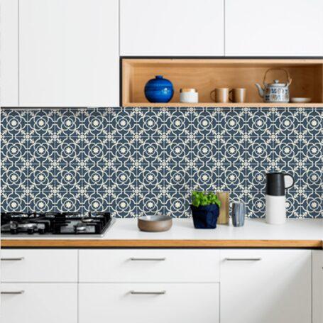 A modern kitchen featuring a patterned blue backsplash, white cabinets, and a wooden shelf with decorative items and kitchenware.