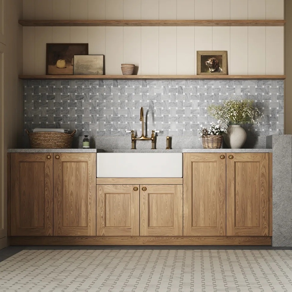 A stylish kitchen with wooden cabinets, a large farmhouse sink, and a light gray tiled backsplash, complemented by decorative plants and photos.