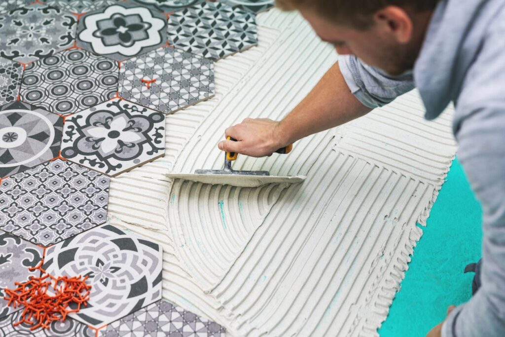 A man lays adhesive for a DIY tile project in his home.