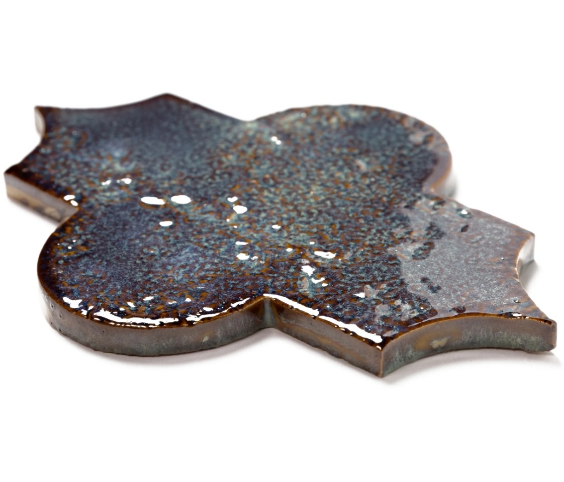 A decorative, glossy tile with a unique shape and an iridescent surface, showcasing a blend of dark colors and shimmering patterns.
