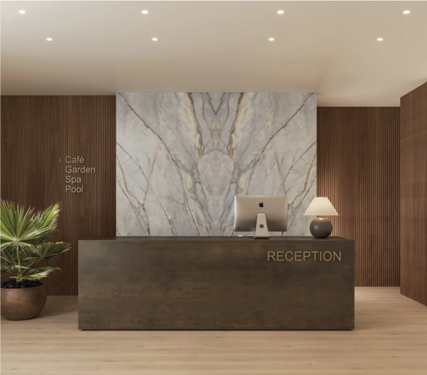 A modern reception area featuring a sleek desk, computer, lamp, and decorative plant in a warm-toned environment.