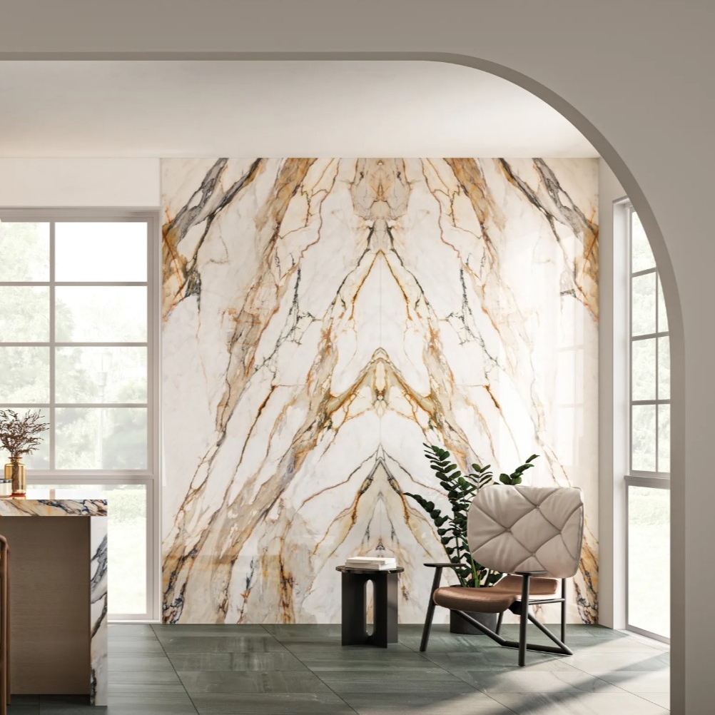 An elegant interior space features a striking marble wall with gold and cream veining, complemented by a modern chair and potted plant.