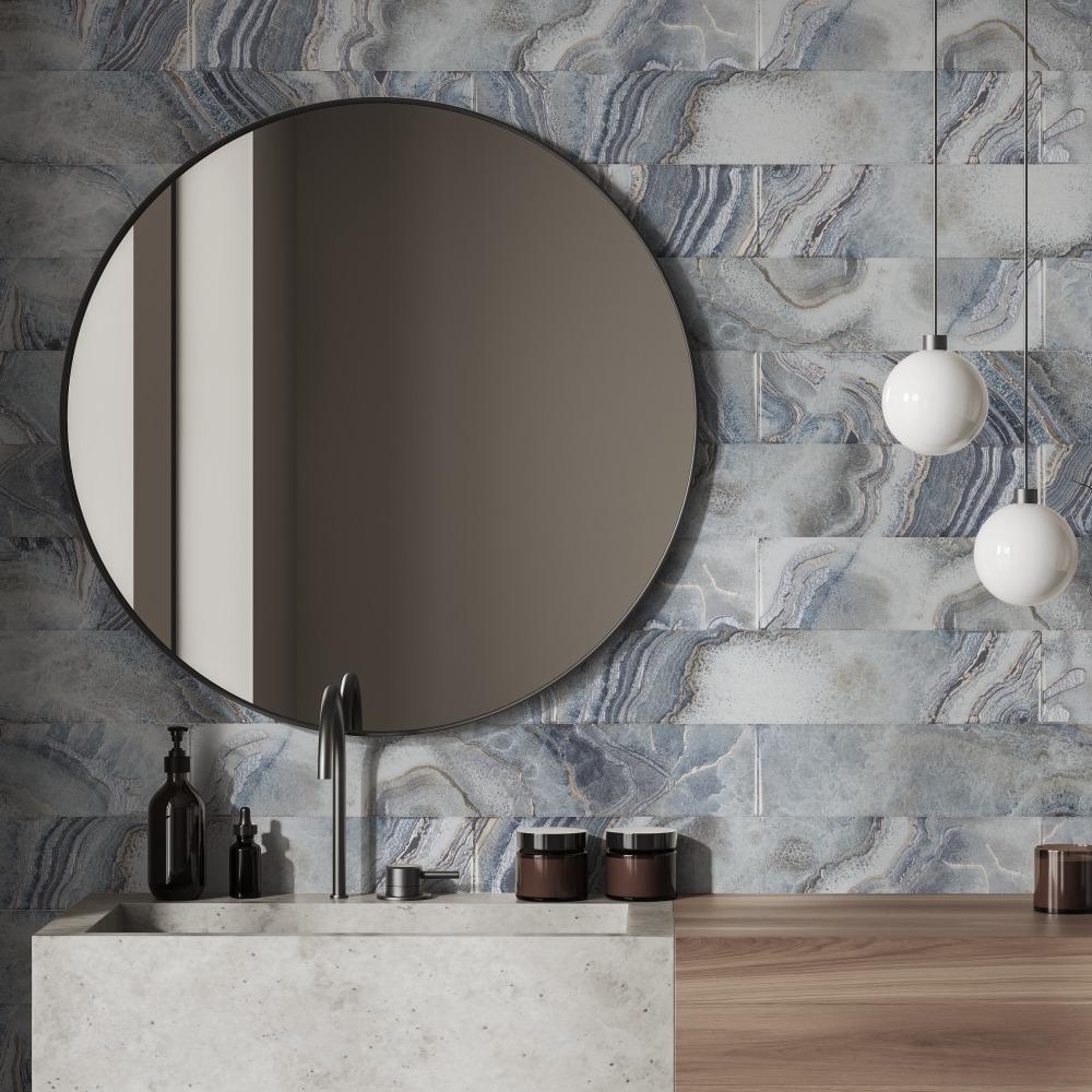 A modern interior featuring a round mirror, a stylish faucet, and elegant pendant lights against a textured blue wall.