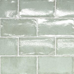 A wall covered in glossy, light green rectangular tiles arranged in a classic brick pattern.