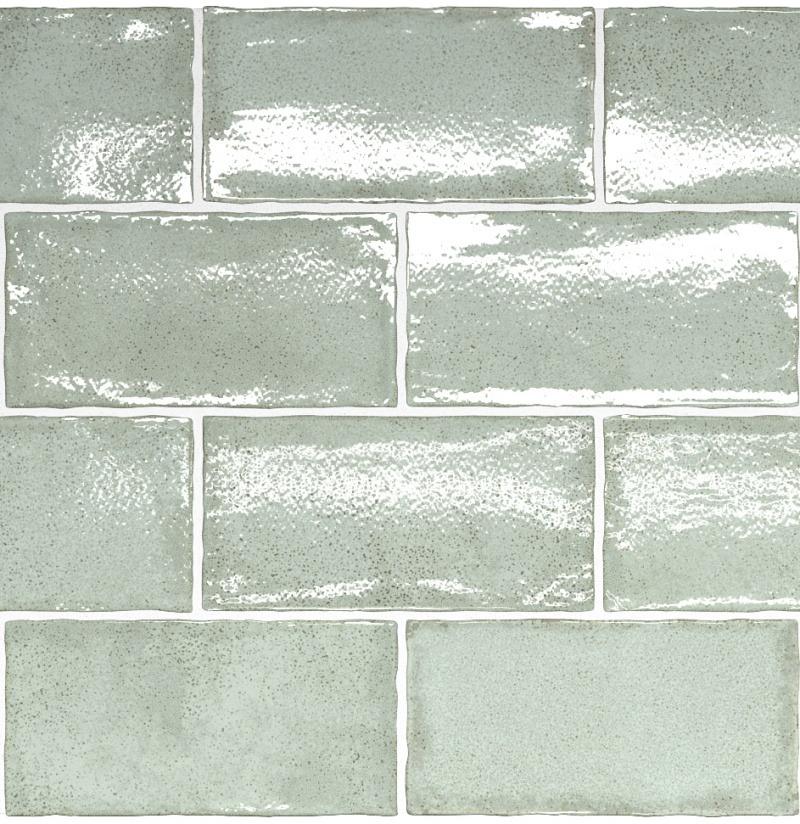 A wall covered in glossy, light green rectangular tiles arranged in a classic brick pattern.