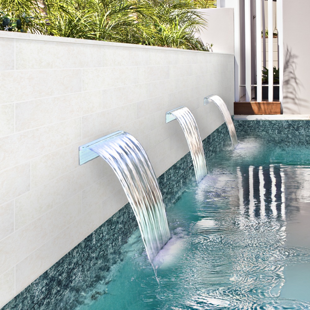 Three modern waterfalls pouring into a turquoise pool, surrounded by lush greenery and a sleek white wall.