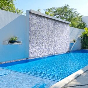 A serene outdoor pool area featuring a cascading water wall, surrounded by greenery and modern architecture.